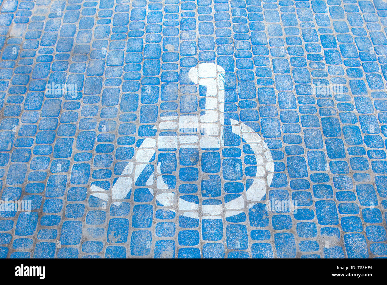 Ansicht von oben auf die Parkplätze für Personen mit Behinderungen. Parkplätze für Behinderte und Rollstuhlfahrer Symbole auf Pflaster. Stockfoto