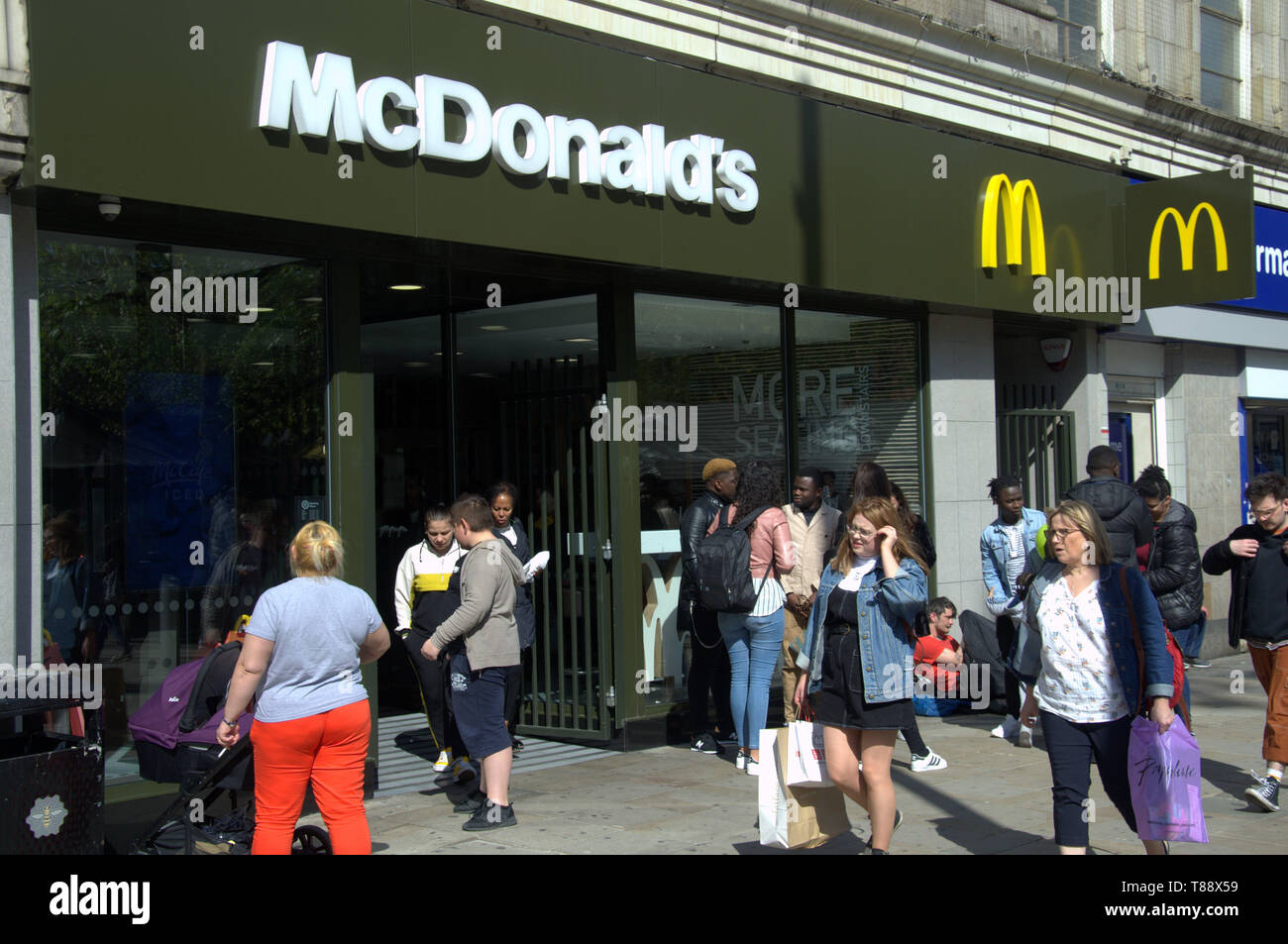 Außenansicht von McDonald's Shop in Piccadilly, Manchester, UK, als Mitglieder der Öffentlichkeit vorbei Stockfoto