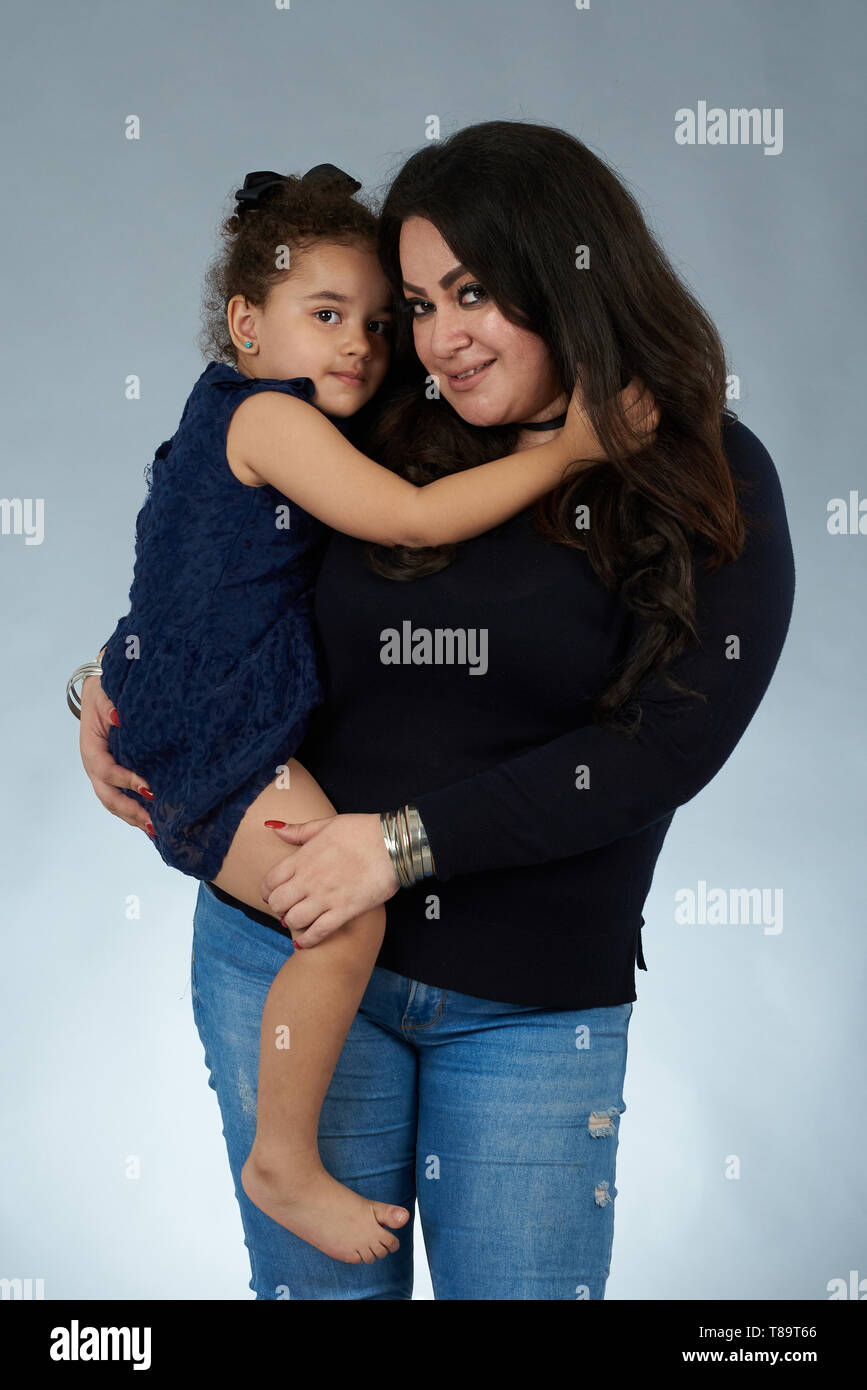 Hispanic Mama mit Tochter auf Grau studio Hintergrund Stockfoto