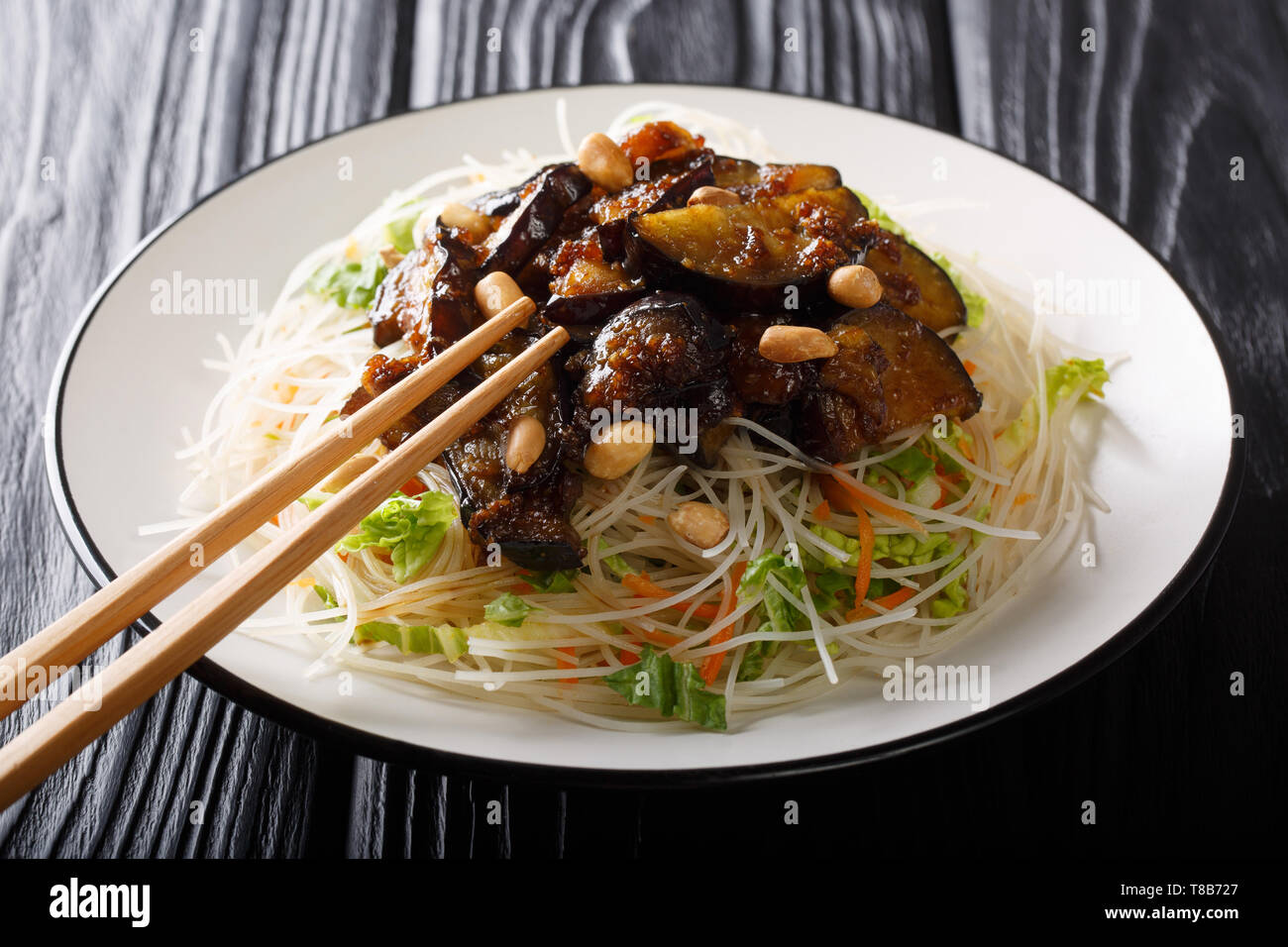 Vegetarische gesunde Reis Nudeln mit Gemüse und karamellisierten Auberginen close-up auf einem Teller auf den Tisch. Horizontale Stockfoto