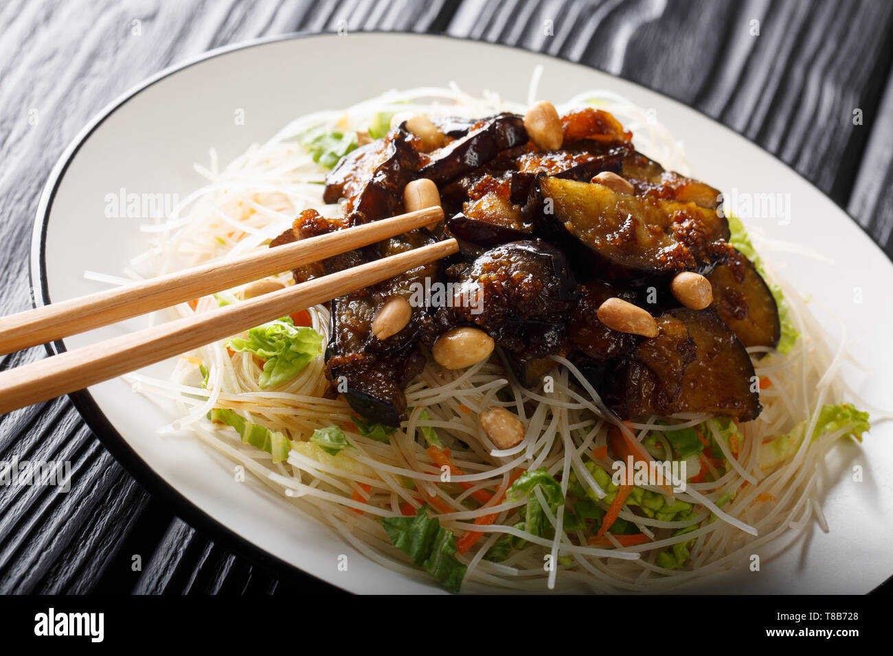 Vietnamesischen stil Reis Nudeln mit Gemüse und karamellisierten Auberginen close-up auf einem Teller auf den Tisch. Horizontale Stockfoto