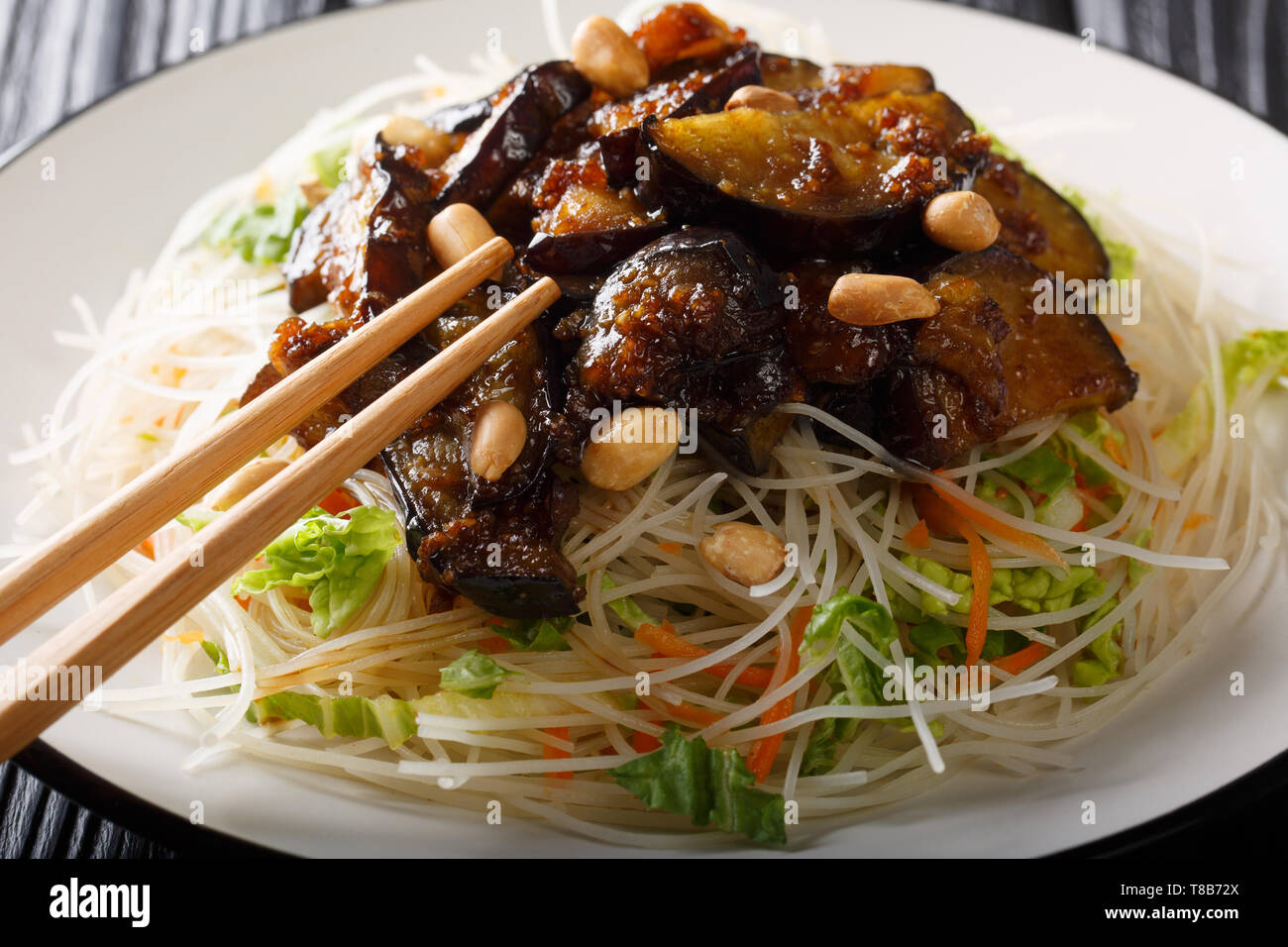 Asiatische Nudeln mit gebratenen Auberginen und Erdnüsse close-up auf einem Teller auf den Tisch. Horizontale Stockfoto