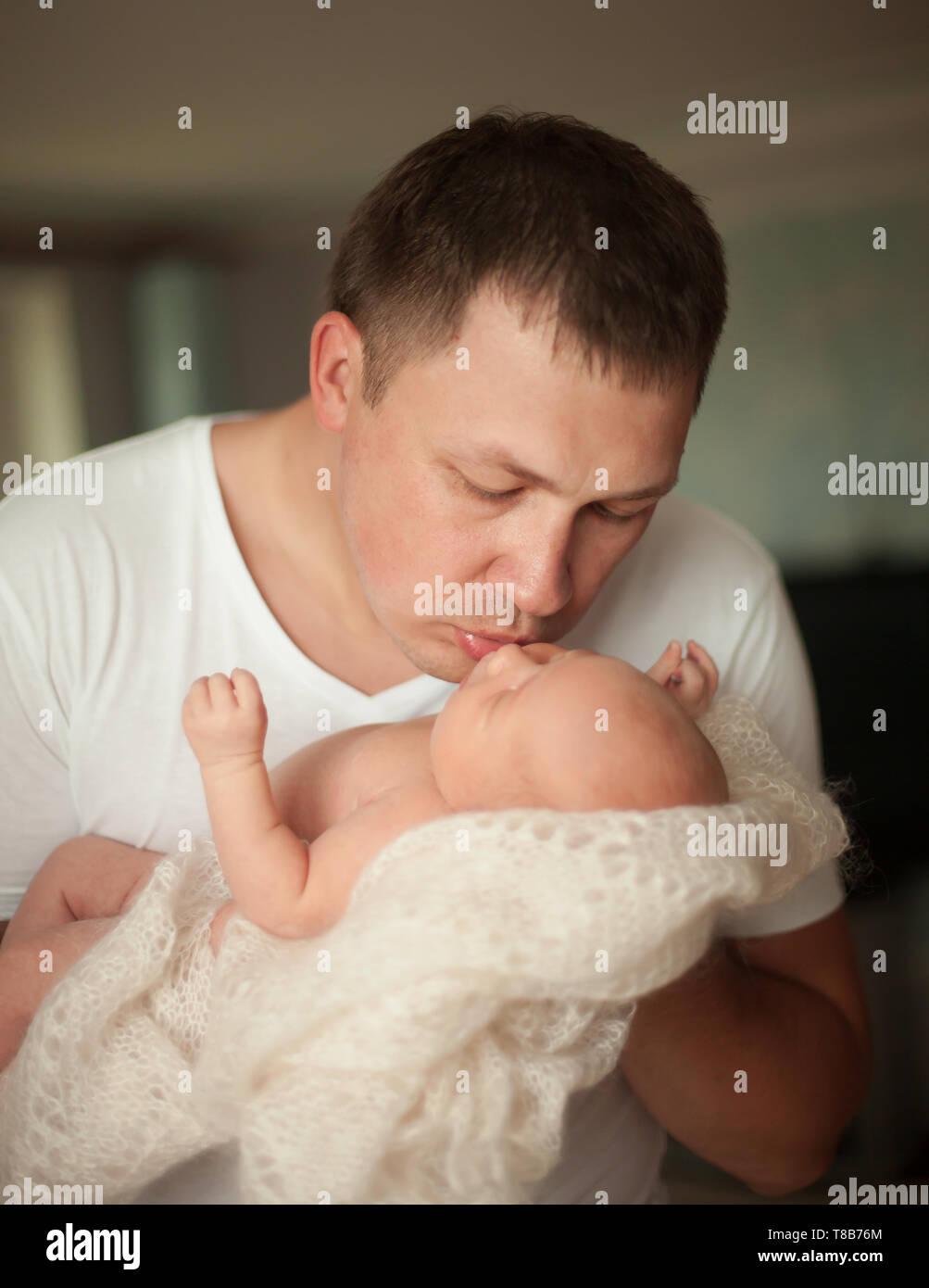 Liebevoller Vater seinem hübschen neugeborenen Tochter Küsse. Das Konzept der väterlichen Liebe Stockfoto