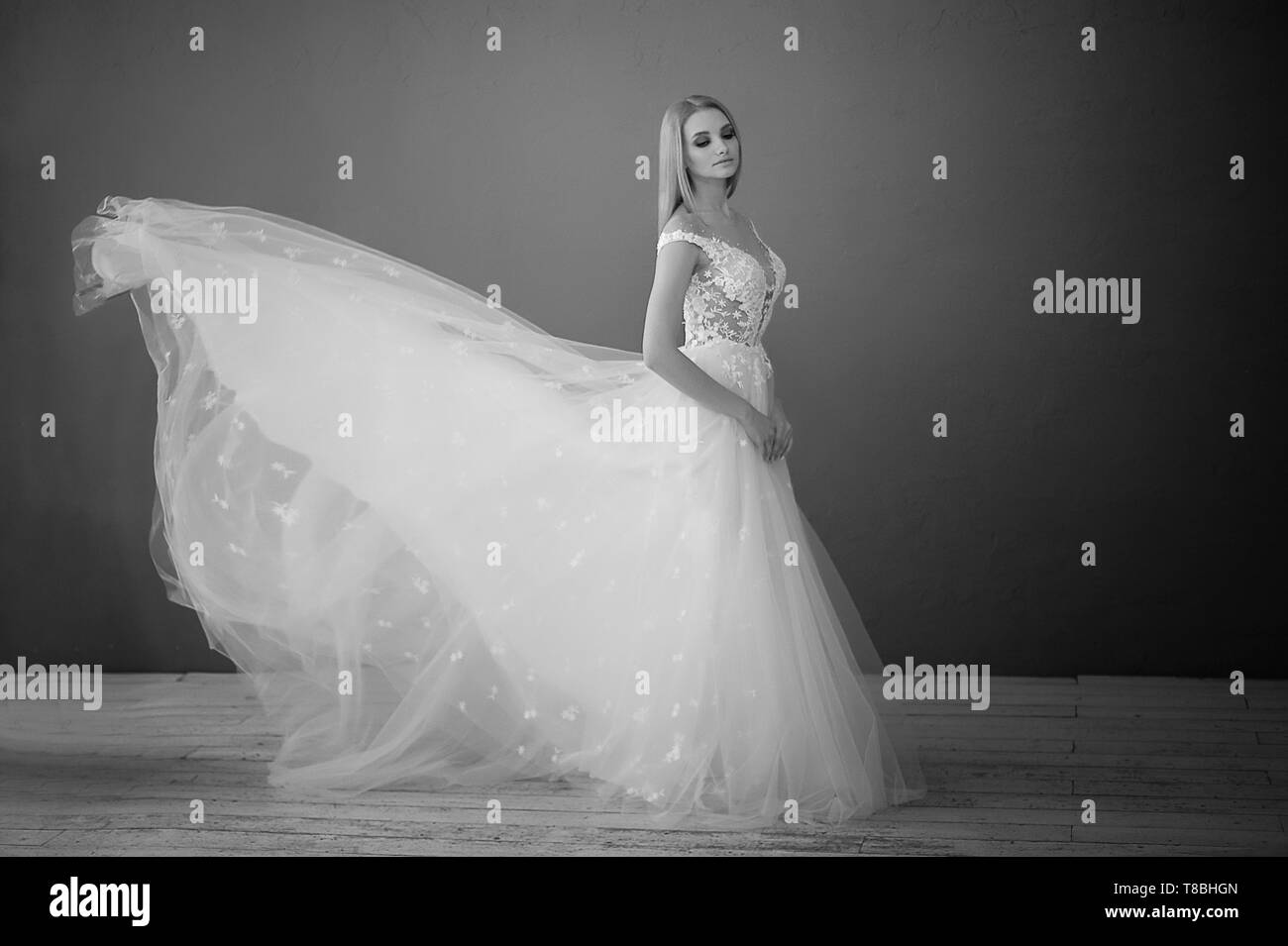 Wunderschöne Spitzenkleid, perfekt sitzend auf der Abbildung. Eine schöne Braut steht in einem Loft Zimmer, wirft ein Rock von einer üppigen Wedding Dress. Stockfoto