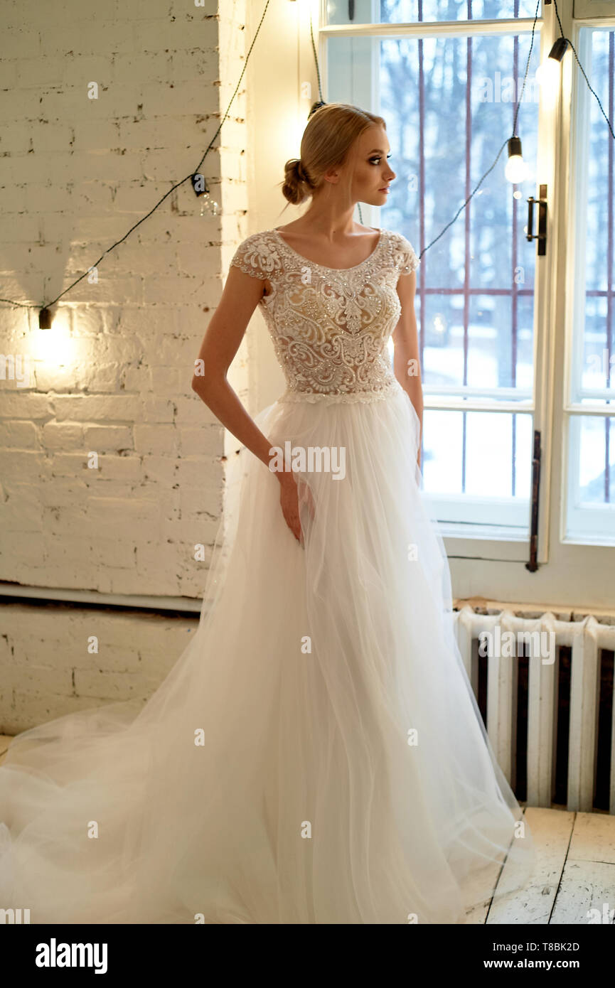 Die Braut in einem weißen Kleid mit besticktem Oberteil, drinnen im Loft-stil. High Key. Stockfoto