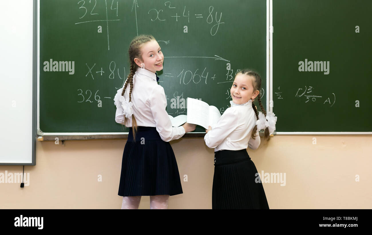 Mädchen Mitschüler schreiben mit Kreide auf die Tafel die Antwort auf die Entscheidung der Schule problem. Stockfoto