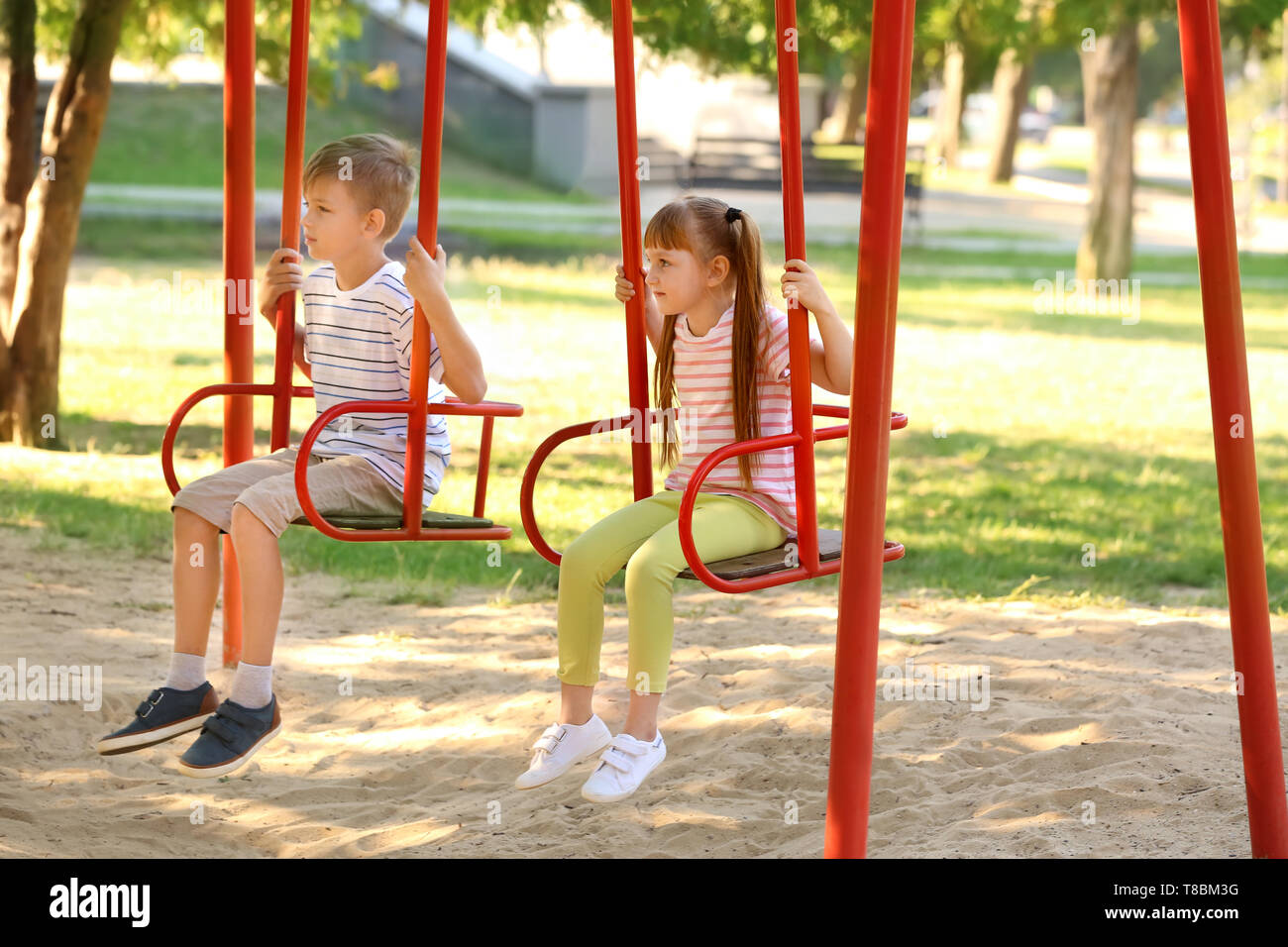 Süße kleine Kinder schwingen im Freien Stockfoto