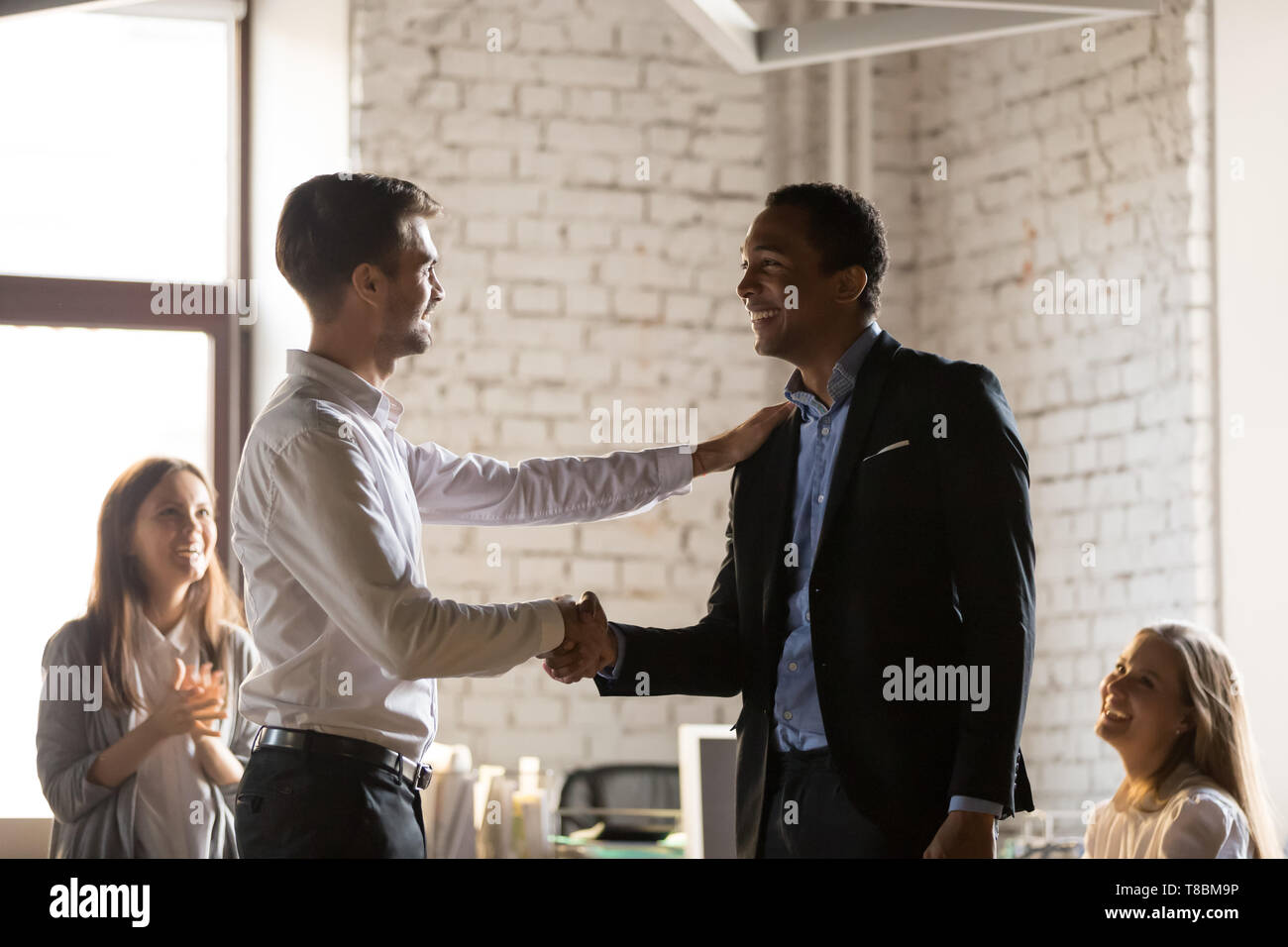 Kaukasische boss gratuliert afrikanischen Mitarbeiter mit Förderung Stockfoto