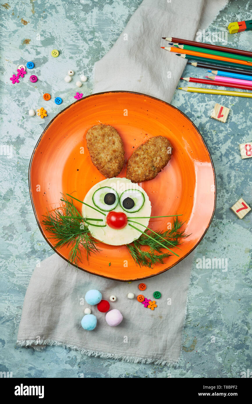 Menü für Kinder, Schnitzel mit Kartoffelbrei in Form eines Hasen Kopf auf  einem orange Platte auf grauem Hintergrund Stockfotografie - Alamy