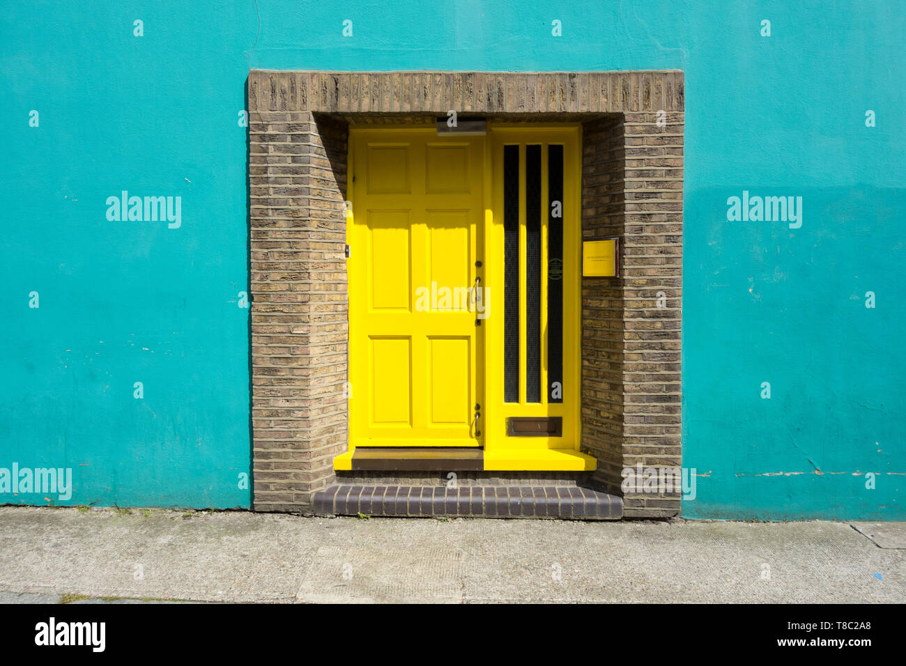 Eingang zum Wohlfühlen Institut - eine gelbe Tür auf eine türkise Wand Stockfoto