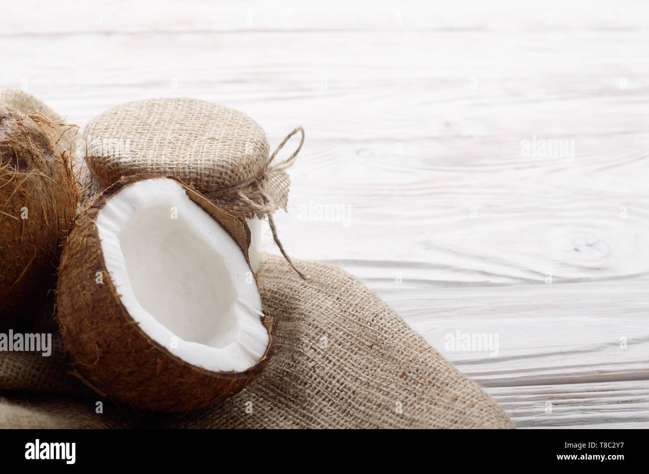 Coconut Shell mit Fleisch auf Hanf Sack auf weißen Küche aus Holz Tisch Stockfoto
