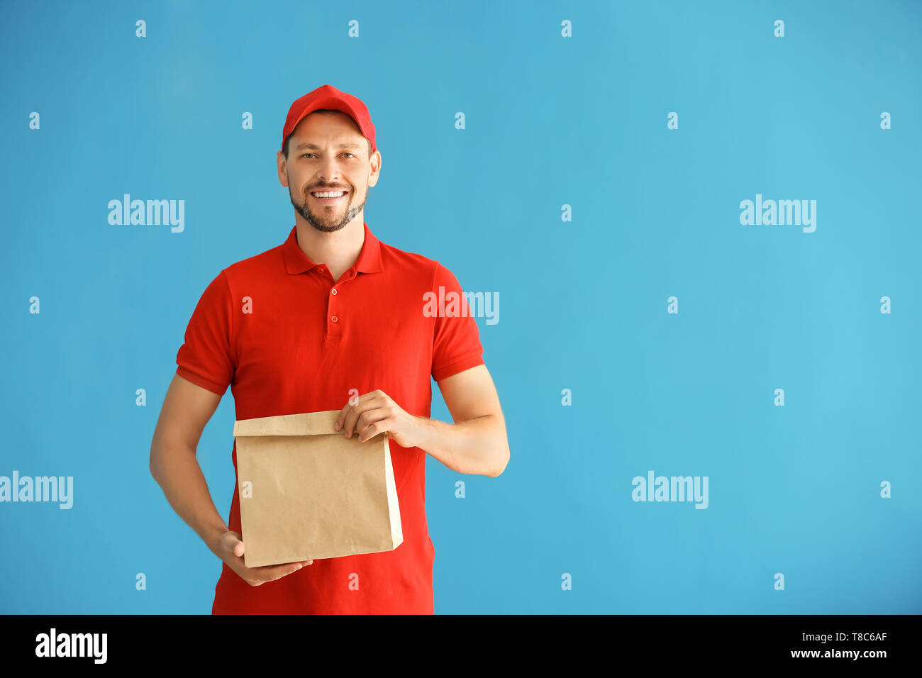 Mann mit papiertüte auf farbigen Hintergrund. Food Delivery Service Stockfoto