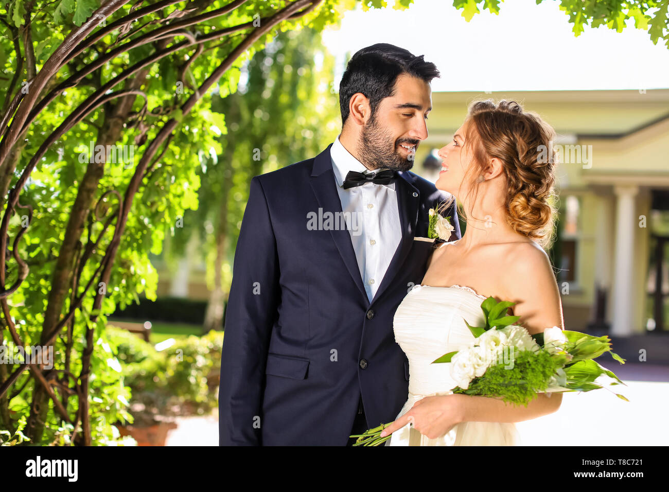Happy Hochzeit paar unter Blumen Bogen im Freien Stockfoto