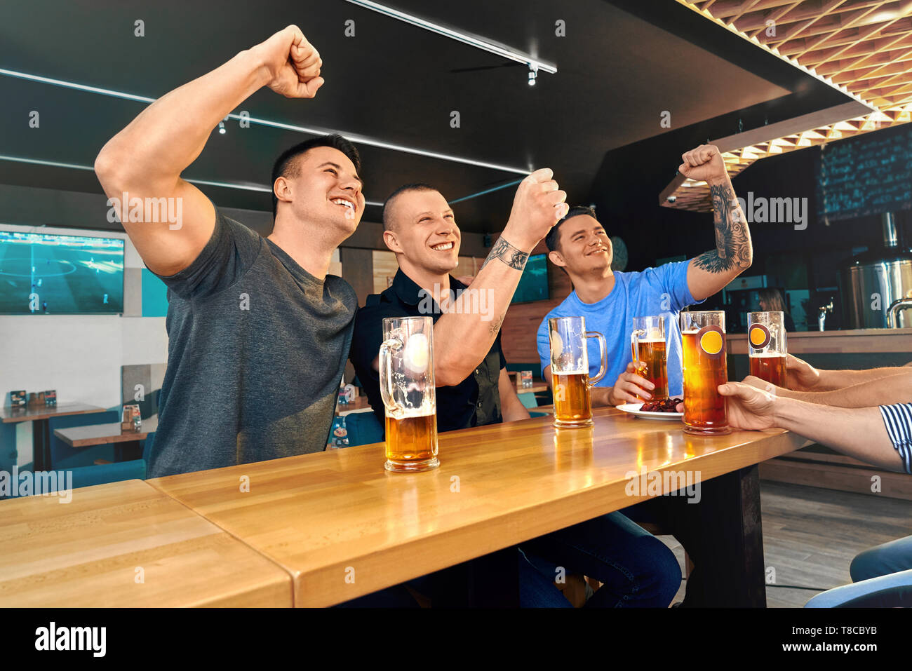 Gerne Freunden im Pub sitzen und beobachten Fußballspiel zusammen. Männliche Freunde jubeln, Lachen und trinken lecker Bier im Cafe am Wochenende. Konzept des Glücks und der Fans. Stockfoto