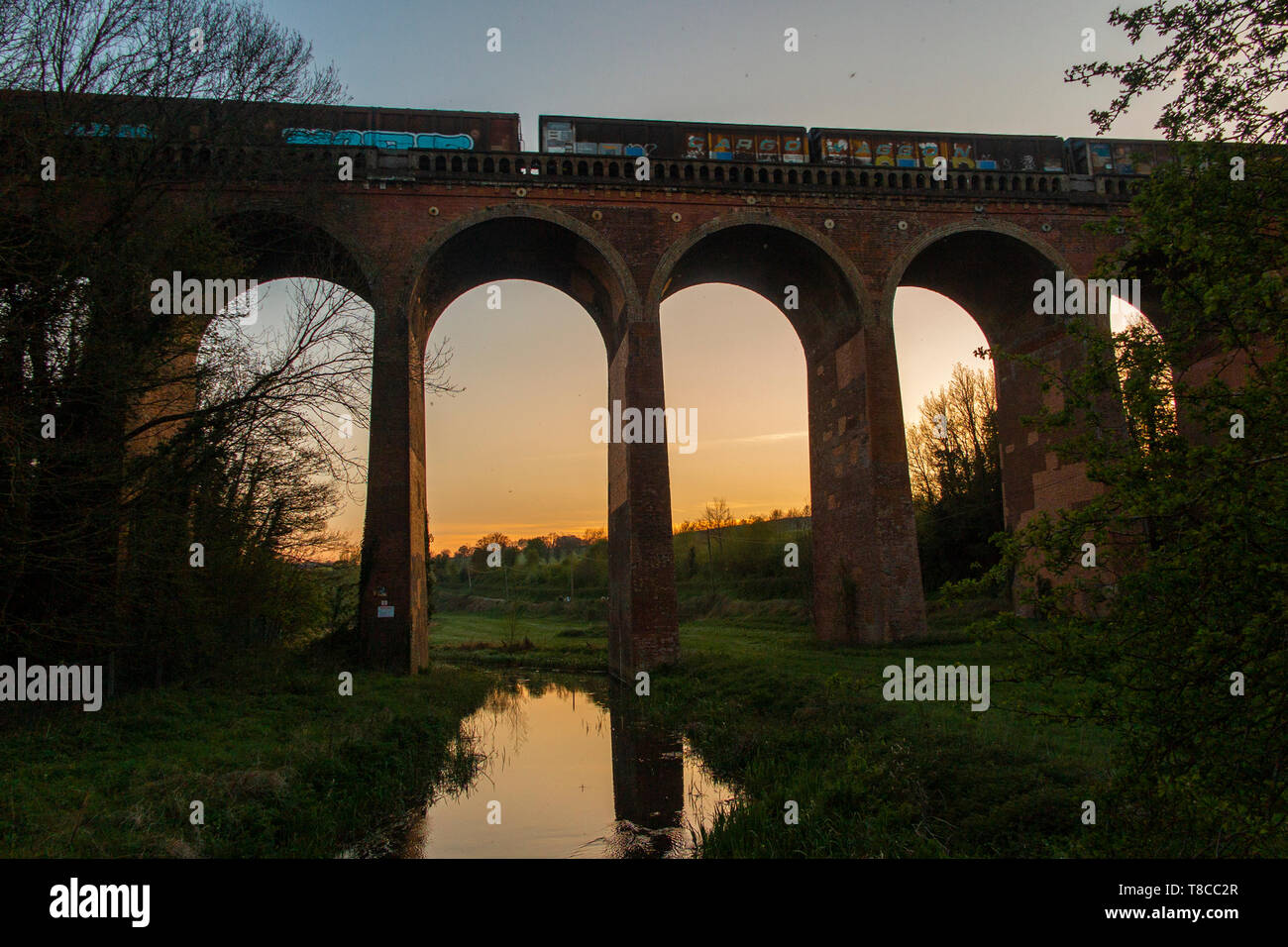 Ein Güterzug kreuze Eynsford Viadukt über den Fluss Darent in Kent bei Sonnenuntergang Stockfoto