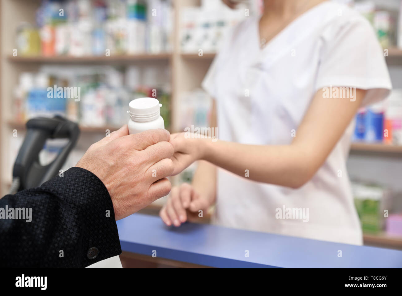 Apotheker arbeiten mit Kunden in der Pharmazie an der Theke an. Frau geben client Medikamente. Mann kaufen Tabletten von der Krankheit. Hand des Client Holding weiße Pille Flasche. Stockfoto