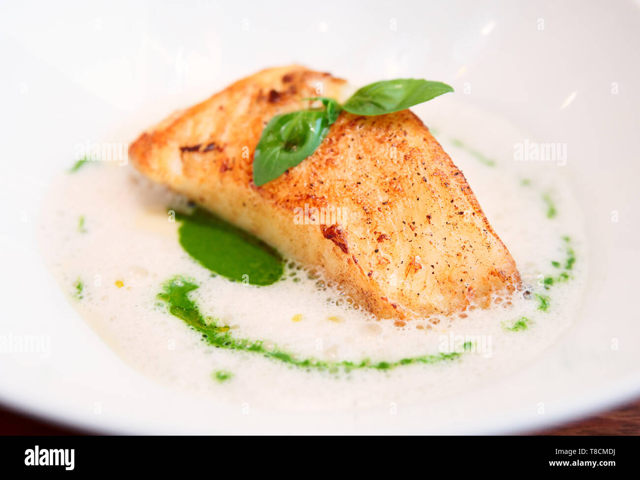 Gedünstetes Fischfilet mit Brühe Soße auf Platte Stockfoto