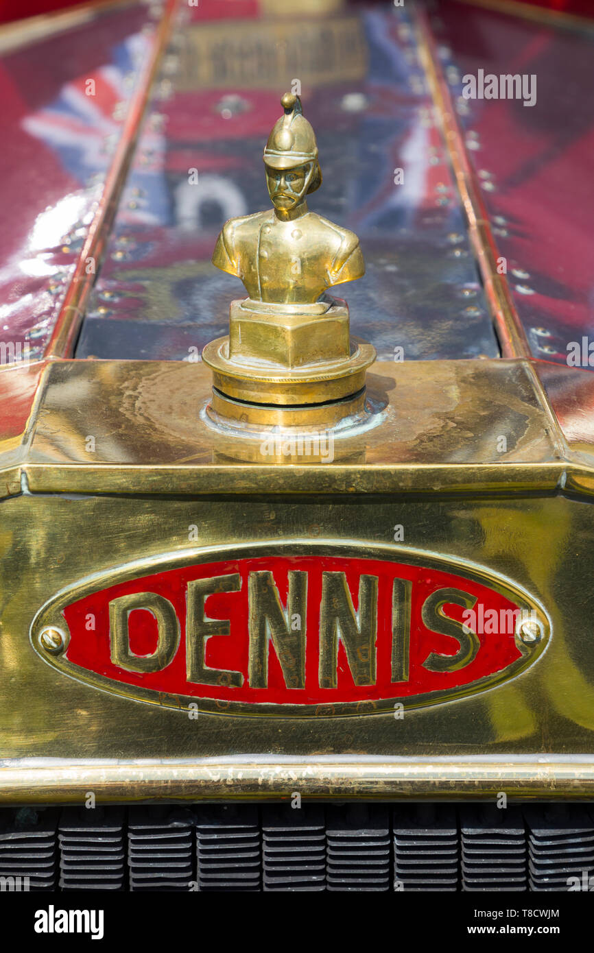 Feuerwehrmann Maskottchen Messing Abzeichen / kühlerdeckel / Logo / Wappen über dem vorderen Kühlergrill auf einem Dennis vintage classic Fire Engine Appliance, auf ein klassisches Fahrzeug Rallye. Großbritannien Stockfoto