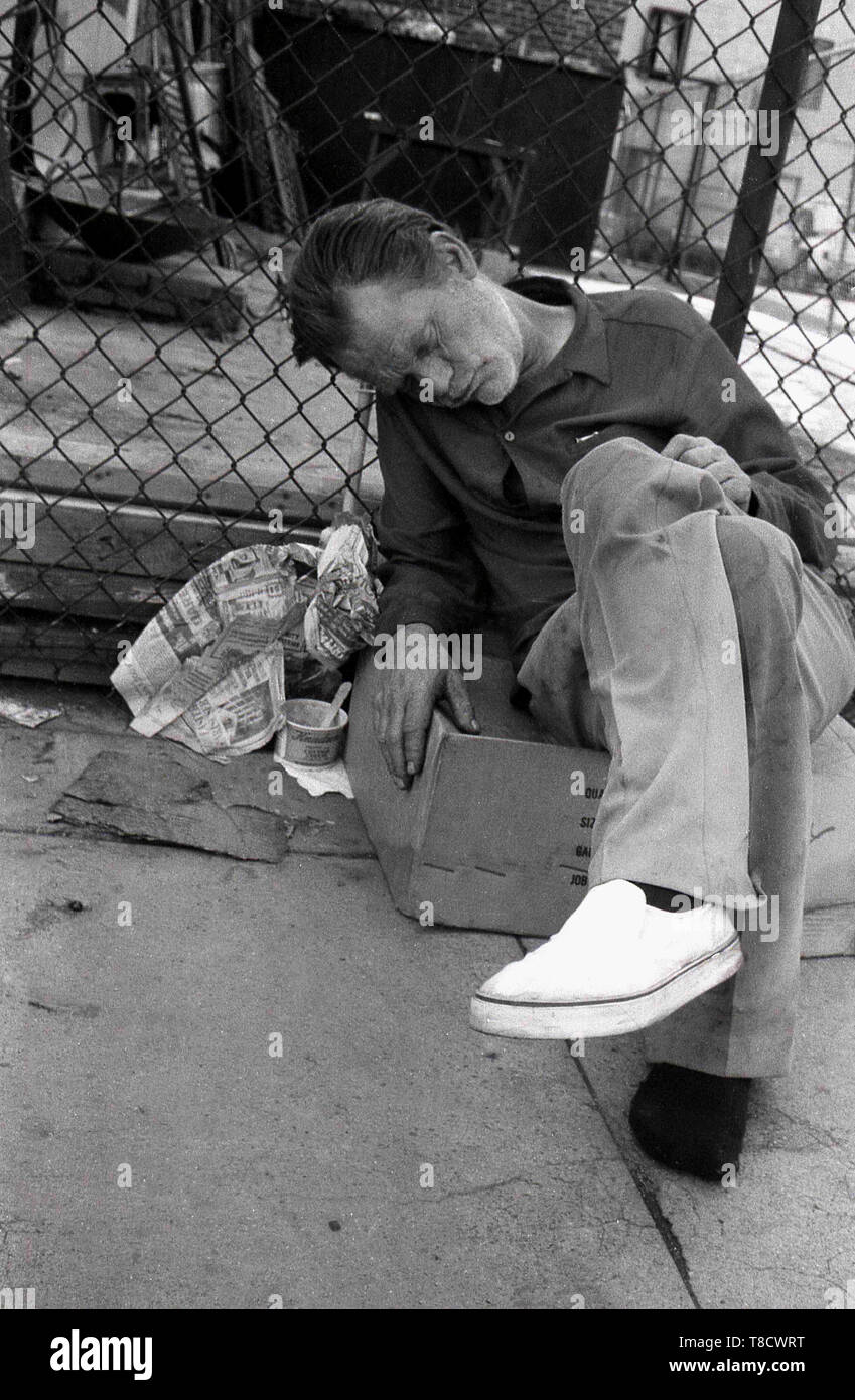 1970er Jahre, Los Angeles, USA, Straßenmenschen, Bild zeigt einen Obdachlosen, der auf einem Karton saß und auf dem Bürgersteig schlief. Teile von LA, bekannt als „Pappstadt“, sind Zeugen einer großen Anzahl verzweifelter, hilfloser Obdachloser, die draußen auf der Straße eine Hand-in-Mund-Existenz leben. Stockfoto