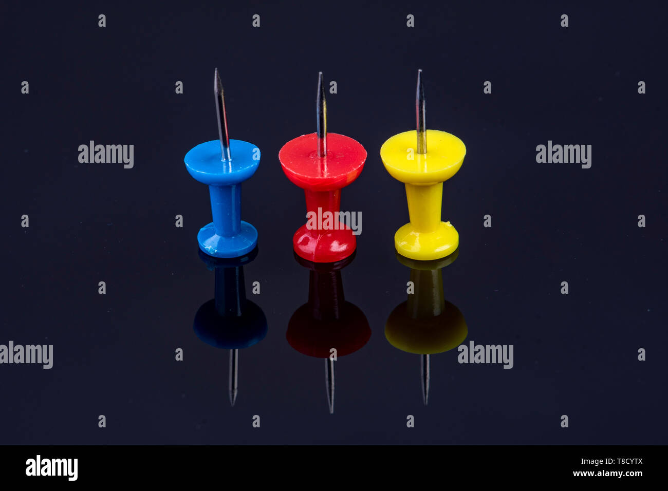 Drei Stifte in der Farbe Blau, Rot und Gelb auf schwarzem Hintergrund Stockfoto