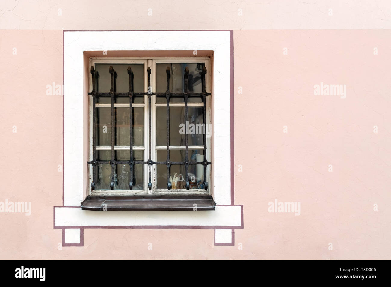 Rechteckiges Fenster mit gusseisernen Balken auf die rosa Wand in der Altstadt von Riga. Stockfoto