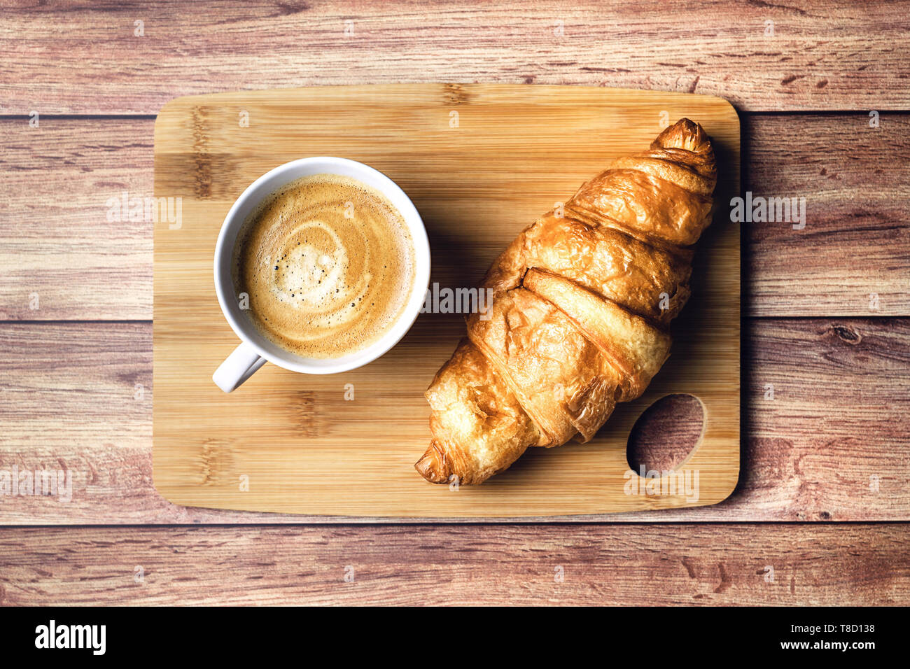 Perfektes Frühstück mit Croissant und Kaffee auf Holztisch. Im rustikalen Stil. Ansicht von oben. Stockfoto