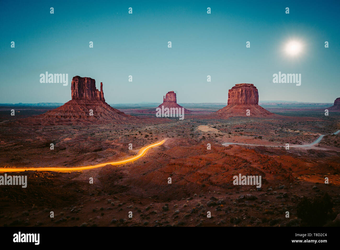 Klassische Panoramablick auf den malerischen Monument Valley mit dem berühmten Mittens und Merrick Butte mit Licht in der Nacht Spuren im Sommer, Arizona, USA Stockfoto