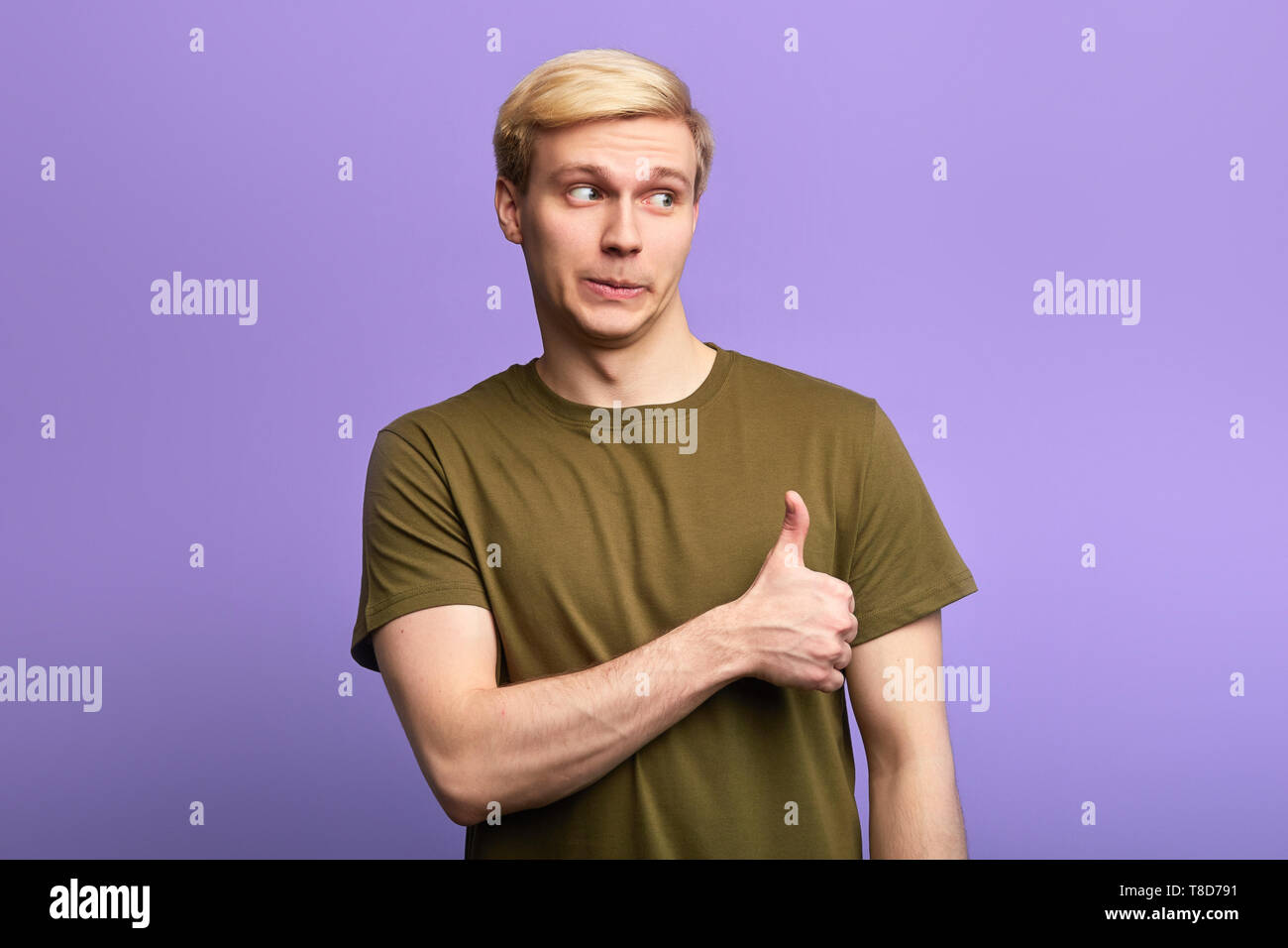 Glücklicher Mann zeigt Daumen oben unterzeichnen Vereinbarung zum Ausdruck bringt, Beifall seinen Freund, beiseite schaut. Über violett Hintergrund isoliert, Studio gedreht. Stockfoto