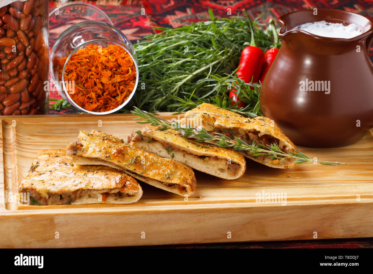 Khachapuri /Lobiani - traditionelle georgische/armenische Küche - Brot gefüllt mit roten Bohnen und serviert mit fermentierter Milch auf einem Holzbrett. Stockfoto