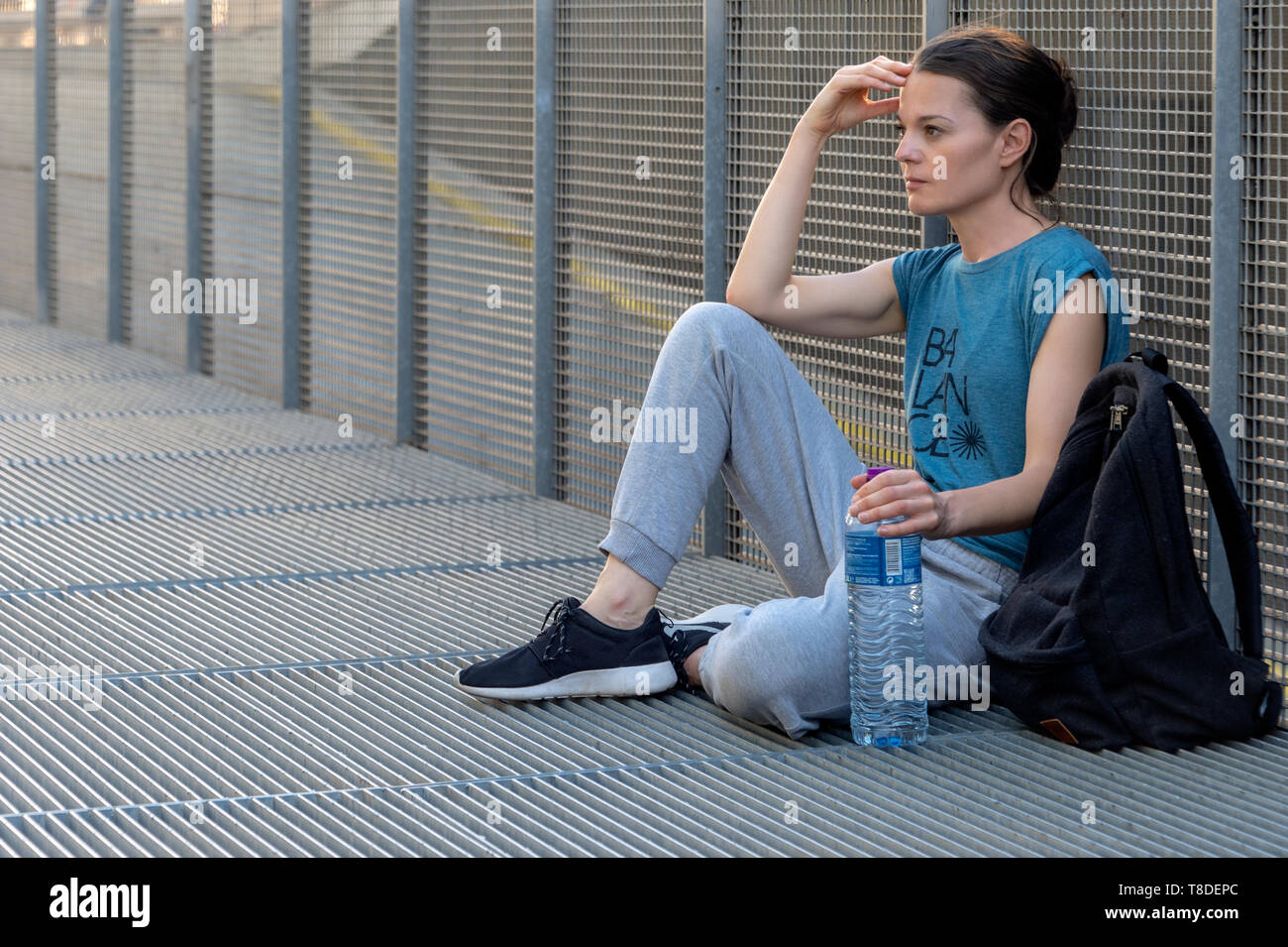 Sportlich fit Frau sitzt und sich mit einer Flasche Wasser, denken. Stockfoto