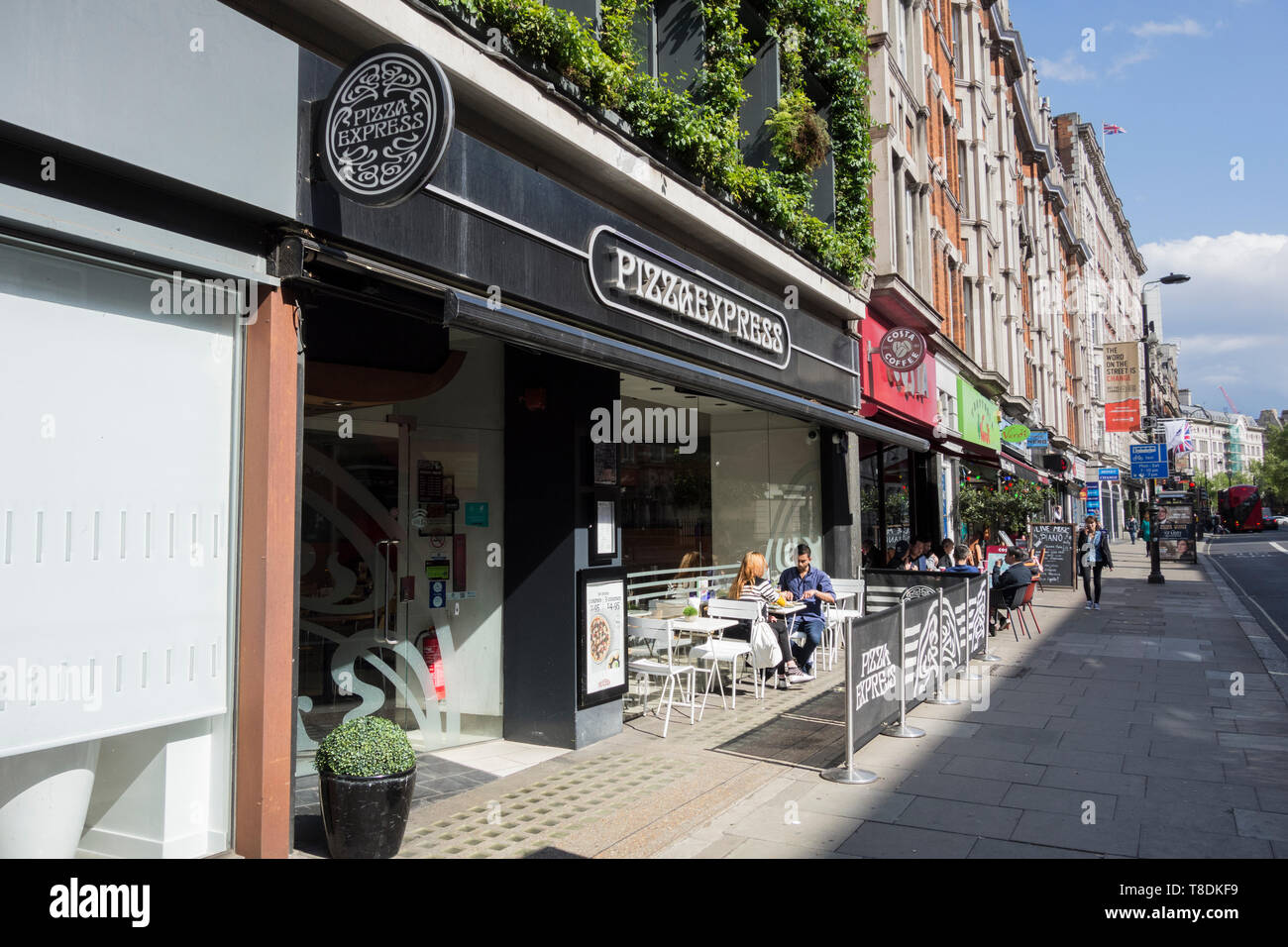 Ein Paar, das außerhalb von Pizza Express in Southampton Row, Bloomsbury, London, Großbritannien, isst Stockfoto