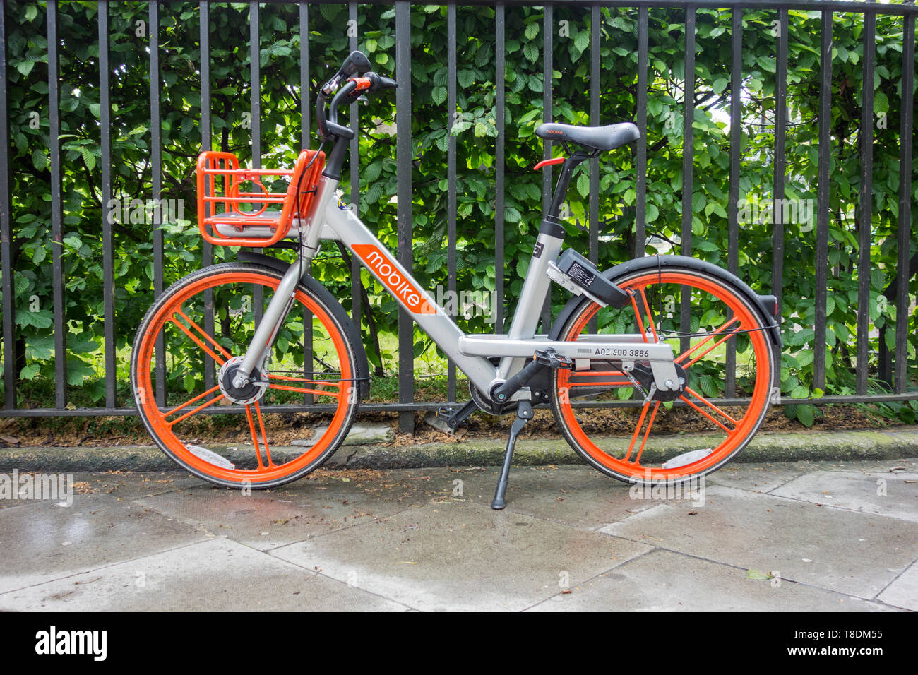 Eine Chinesische bike-sharing (mobike Bike) gegen Geländer in einem Londoner square lehnend. Stockfoto