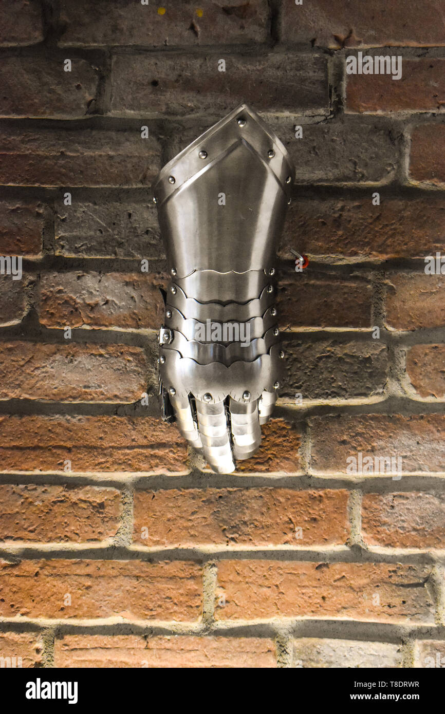 Mittelalterliche metall Handschuh, Detail der Teil des antiken Rüstung, Detail des Krieges. Shining Bügeleisen Handschuh gegen die Mauer Hintergrund Stockfoto