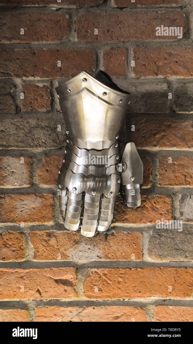 Mittelalterliche metall Handschuh, Detail der Teil des antiken Rüstung, Detail des Krieges. Shining Bügeleisen Handschuh gegen die Mauer Hintergrund Stockfoto