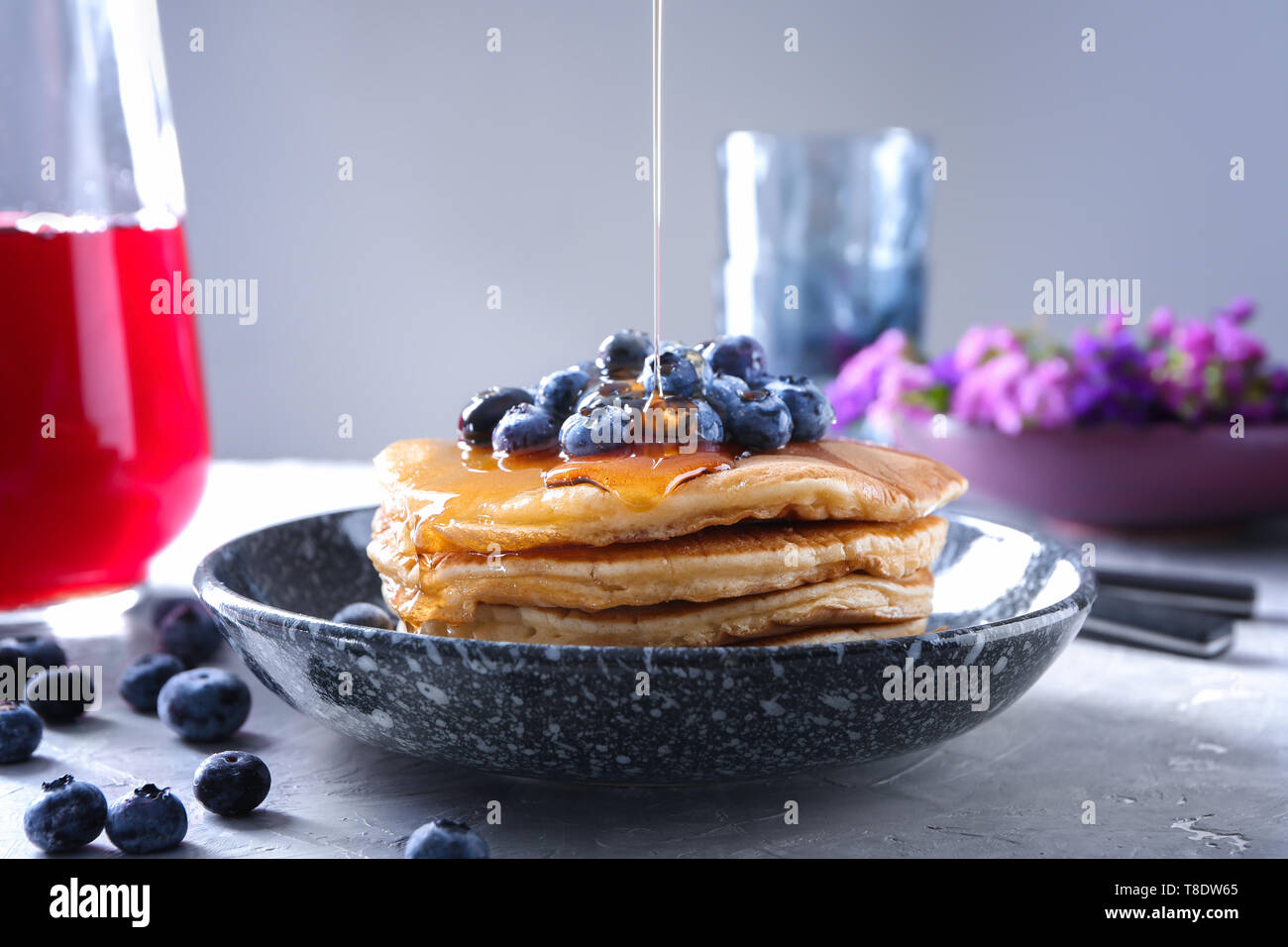 Das Gießen von Honig auf leckere Pfannkuchen mit Heidelbeeren auf Licht ...