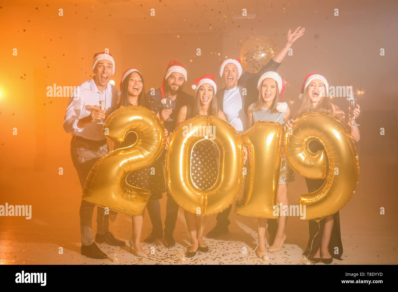 Junge Menschen mit goldenen Luftballons an der Weihnachtsfeier Stockfoto