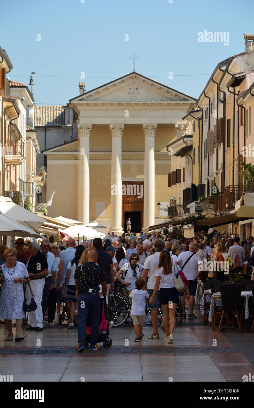 Touristen auf der Piazza Giacomo Matteotti mit der Kirche San Nicolo und Severo Bardolino am Gardasee - Italien. Stockfoto