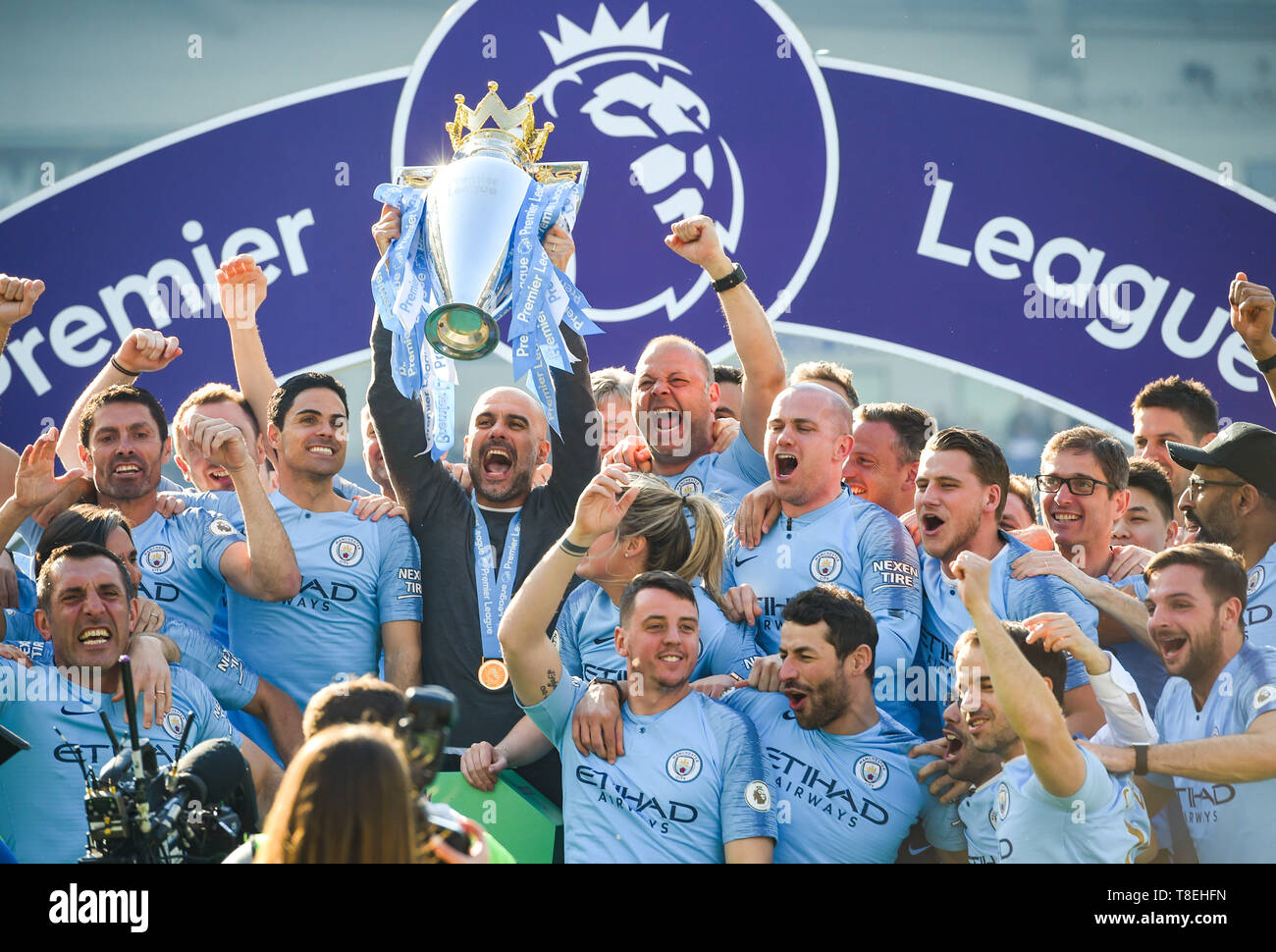 Manchester City Manager Pep Guardiola hebt die Trophäe der Premier League mit seinen Mitarbeitern nach dem Spiel der Premier League zwischen Brighton & Hove Albion und Manchester City im American Express Community Stadium, 12. Mai 2019 Foto Simon Dack/Tele Images Editorial Use only. Kein Merchandising. Für Fußballbilder gelten Einschränkungen für FA und Premier League. Keine Nutzung von Internet/Mobilgeräten ohne FAPL-Lizenz. Weitere Informationen erhalten Sie von Football Dataco Stockfoto