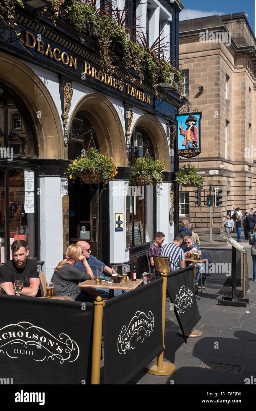 Kunden, genießen Sie einen Drink in der Sonne außerhalb Deacon Brodie's Taverne in der Lawnmarket, Edinburgh, Schottland, Großbritannien. Stockfoto