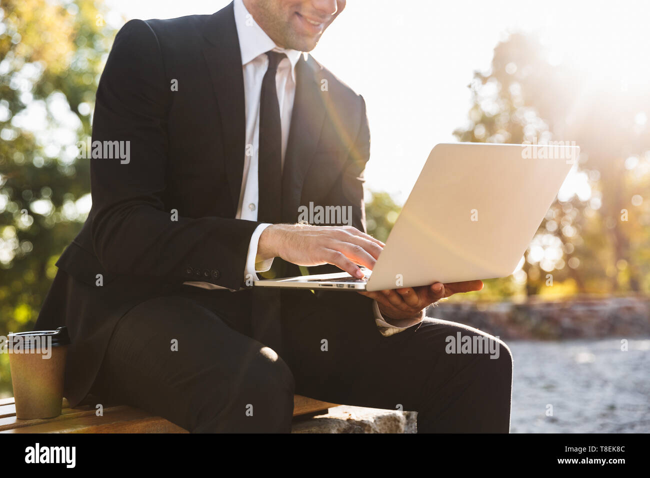 Zugeschnittenes Bild von ein hübscher junger Geschäftsmann Walking im Freien mit Laptop Computer. Stockfoto