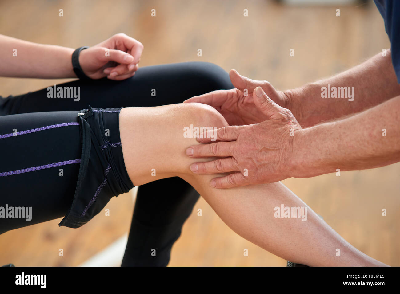 Muskel Belastung während des Trainings. Männliche Hände tun, eine Massage zu weiblichen Knie im Fitnessstudio in der Nähe. Die Behandlung von Muskelkater nach dem Sport ausüben. Stockfoto