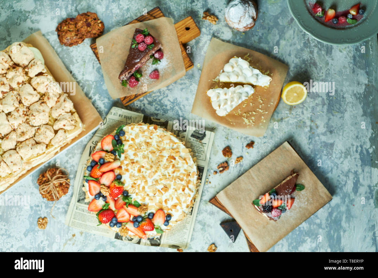 Baiser Kuchen mit Lavendel Sortiment von mehreren Kuchen, dekoriert mit Obst auf Platten Platten und grauer Hintergrund FLATLAY Stockfoto