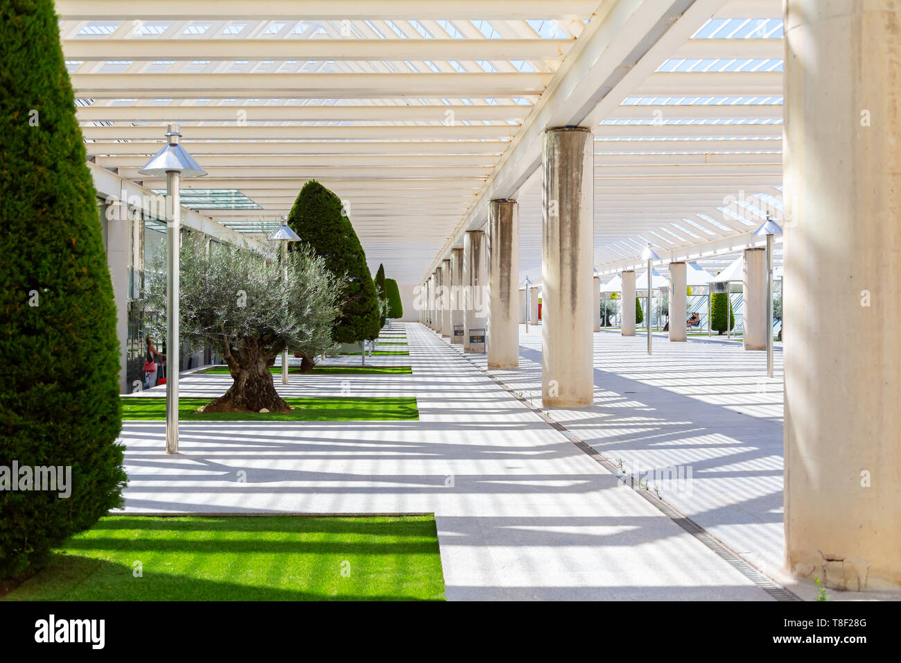 Der Innenhof am Flughafen, ein Platz zum Rauchen und zum Boarding draußen warten. Moderne Architektur mit Metall Säulen und Balken. Mit Nadelbäumen, kleinen Rasenflächen und Pavillon eingerichtet. Stockfoto