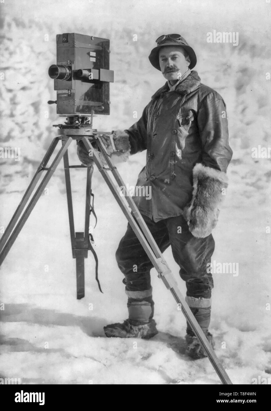Foto zeigt Herbert G. Ponting, full-length Portrait, stehend, nach vorne, mit Film (?) Kamera auf Stativ, während der British Antarctic Expedition, um 1910 Stockfoto