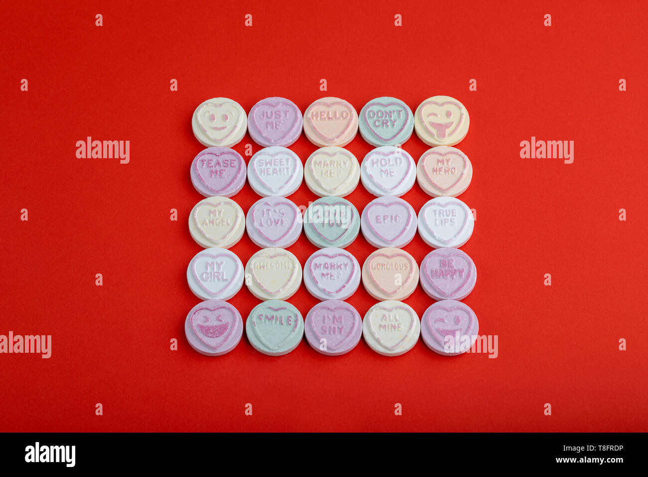 Einem quadratischen Muster der Kinder liebe herz Bonbons auf roten Karton Stockfoto