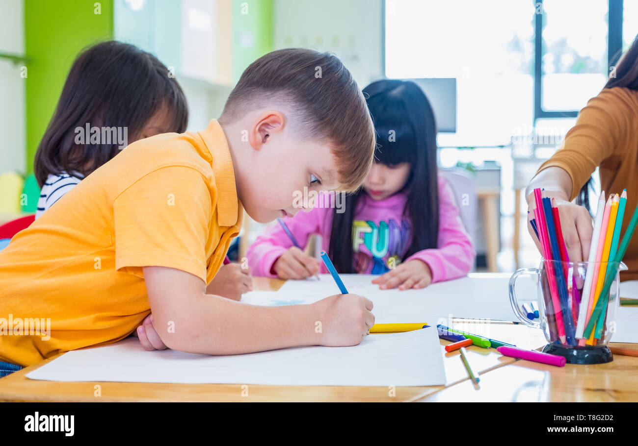 Kaukasische junge Ethnizität Kind lächelnd weiße Lernen im Klassenzimmer mit Freunde und Lehrer im Kindergarten, Schule, Ausbildung Konzept. Stockfoto
