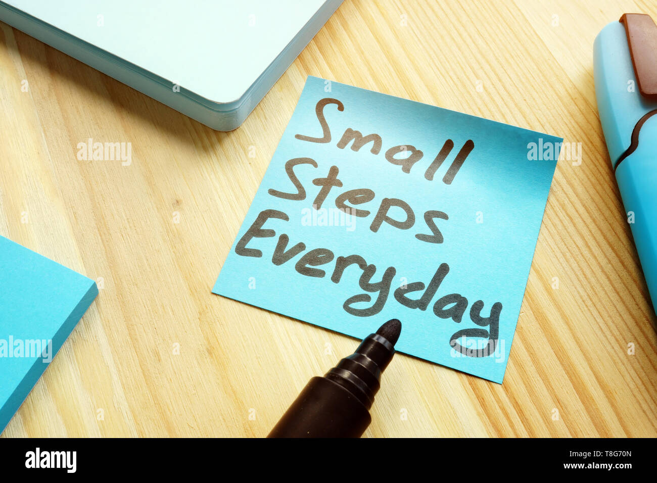 Handschriftliche Zitat kleine Schritte im Alltag auf Tisch. Motivation Konzept. Stockfoto