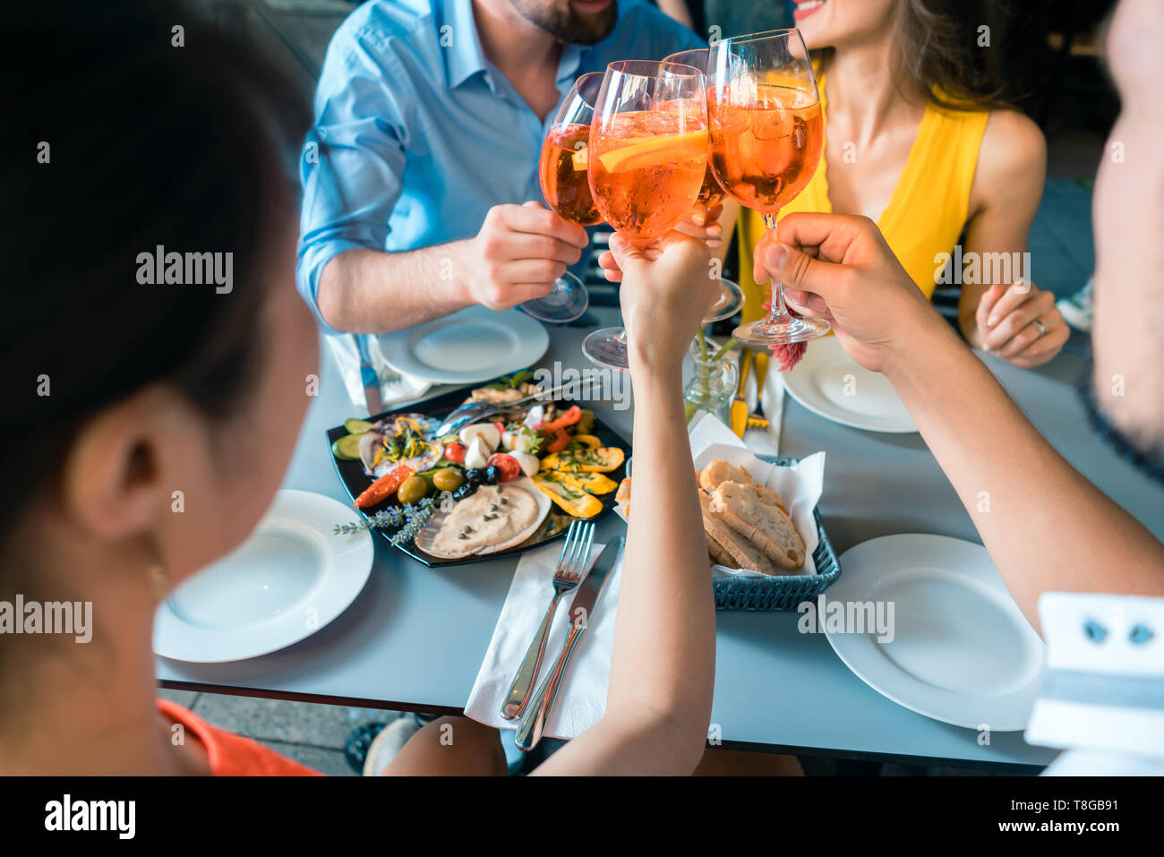 Vier Freunde, die zusammen das Toasten mit einem erfrischenden kalten Getränk Stockfoto