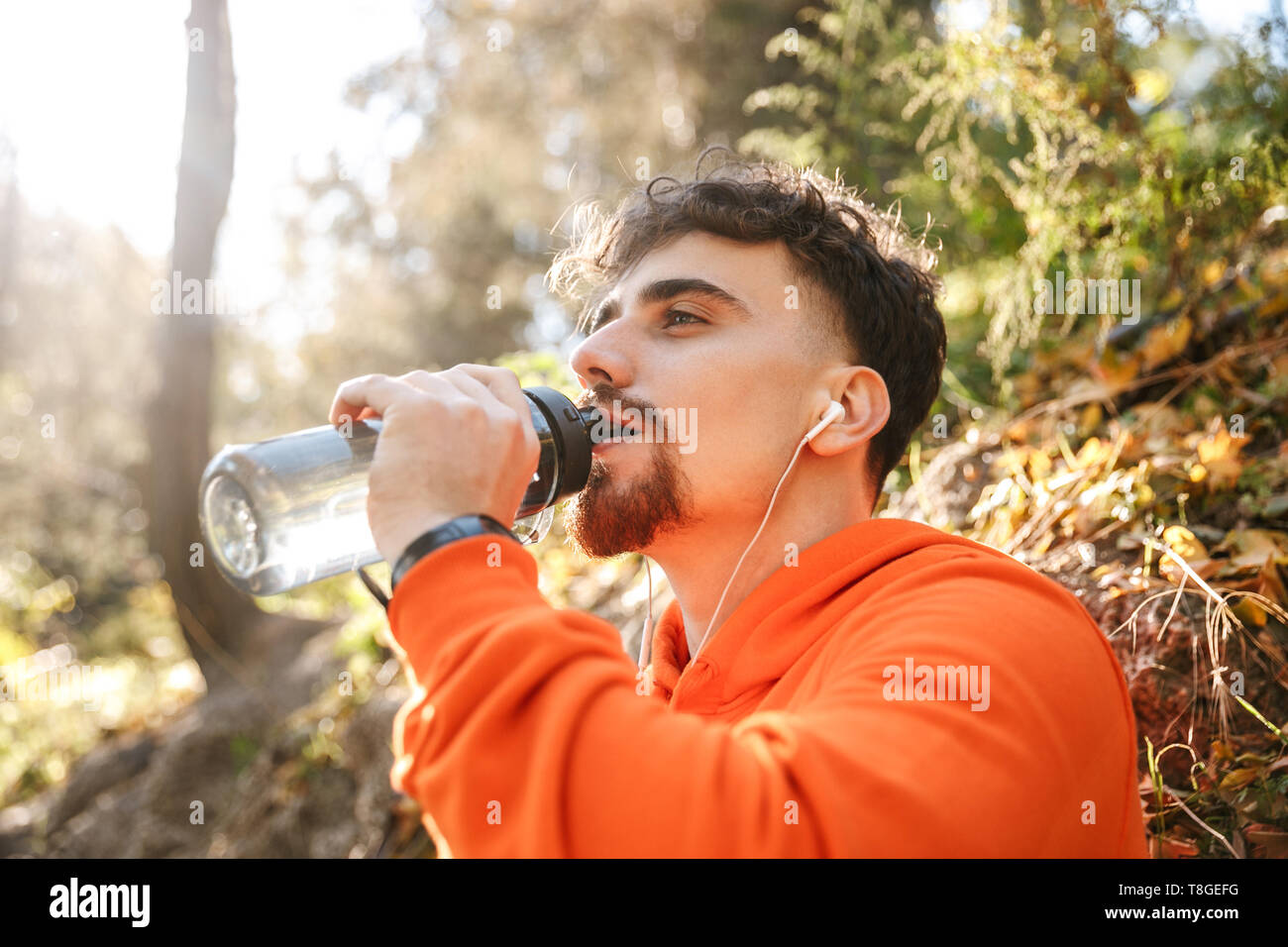 Bild von hübscher junger Mann Sport Fitness runner draußen im Park Trinkwasser. Stockfoto