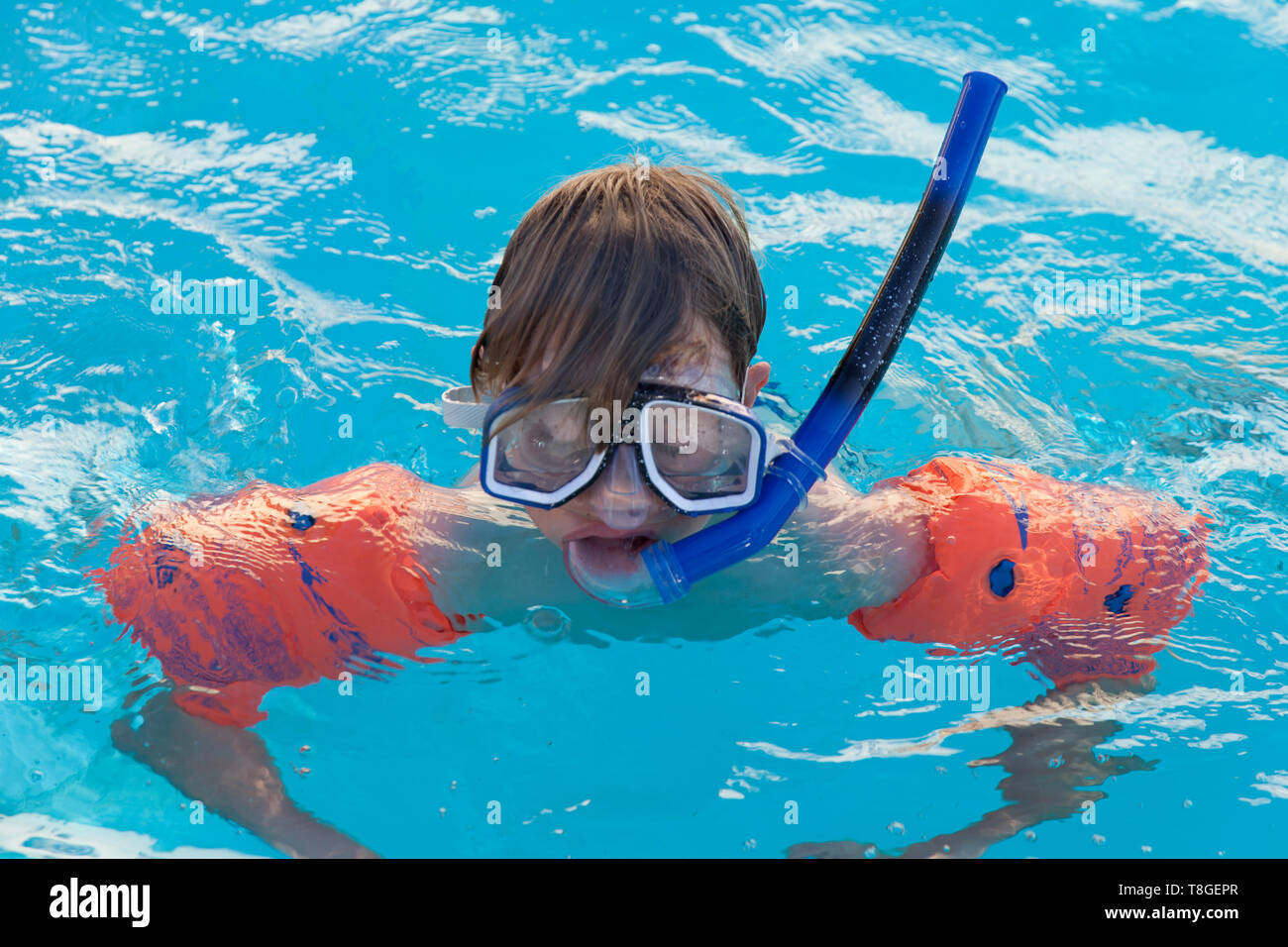 Junge in Pool mit armbinden und Schnorchel und Brille in einem Schwimmbad in der Villa in Griechenland Stockfoto